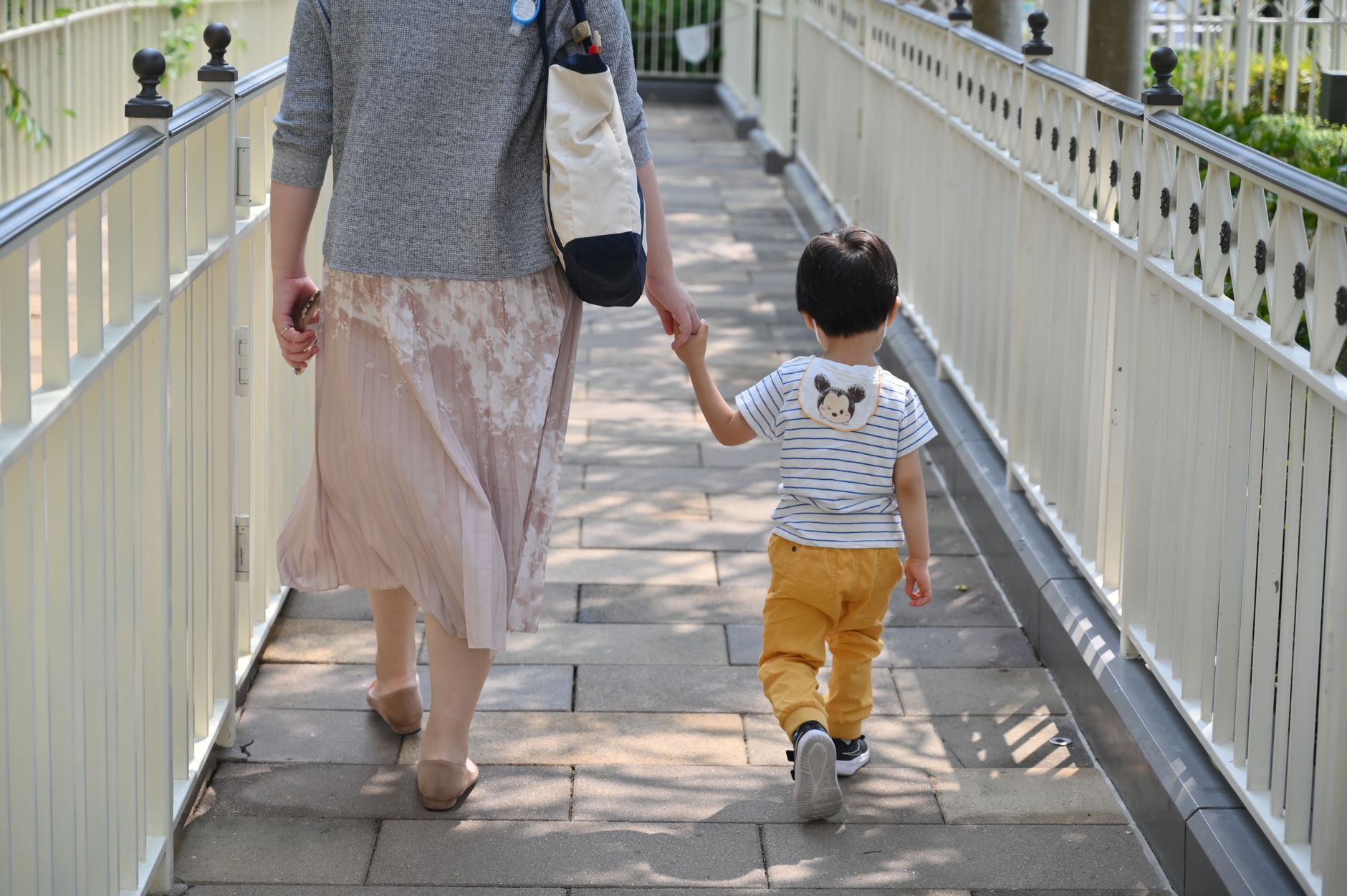 大人と手をつないで歩く子どもの後ろ姿